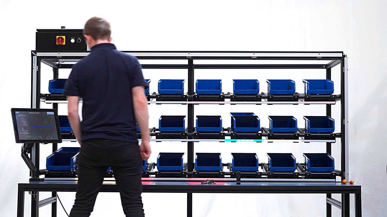 An operator working a Monk Conveyors pick-to-light bin rack