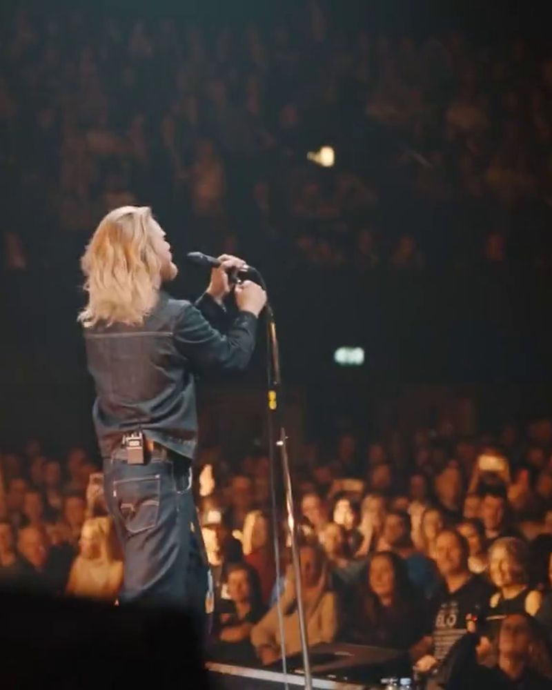 Sam Ryder at the microphone with the Wembley crowd lit behind him