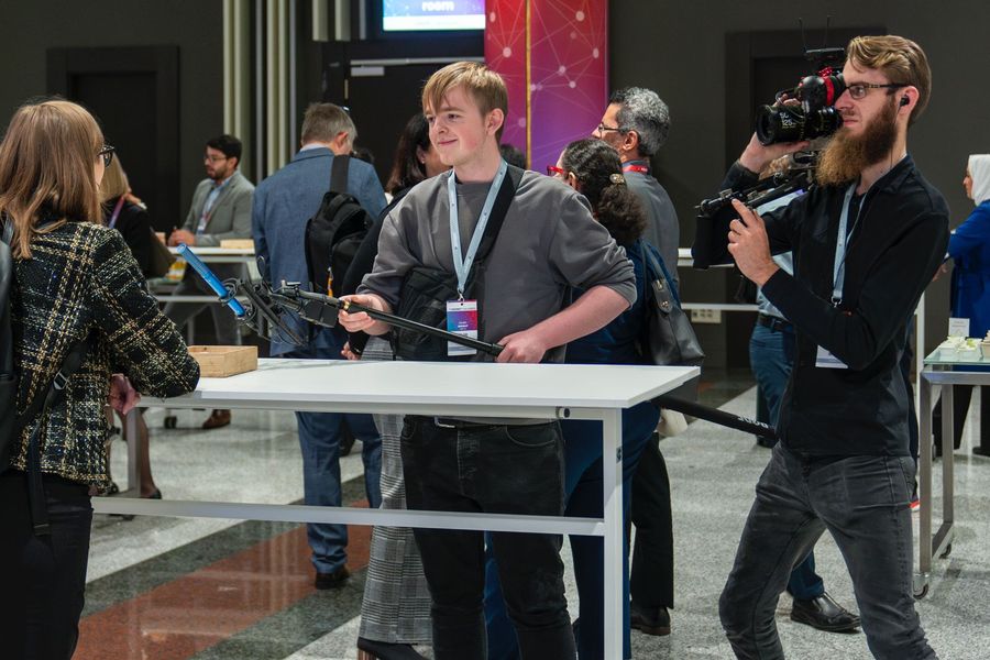 Dan Wright interviewing a guest on an event floor, boom in hand, with a camera operator alongside