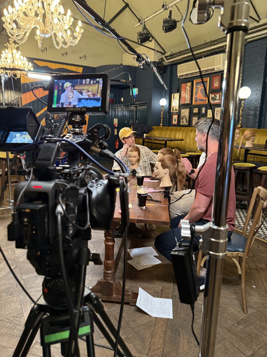 Behind the B camera, the hosts and guest framed on the monitor