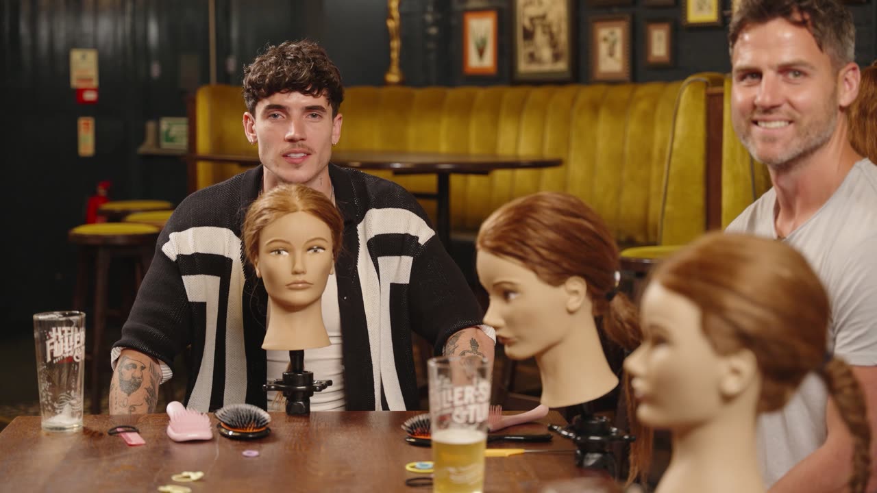 Cam Holmes and a host at the pub table in the cold open