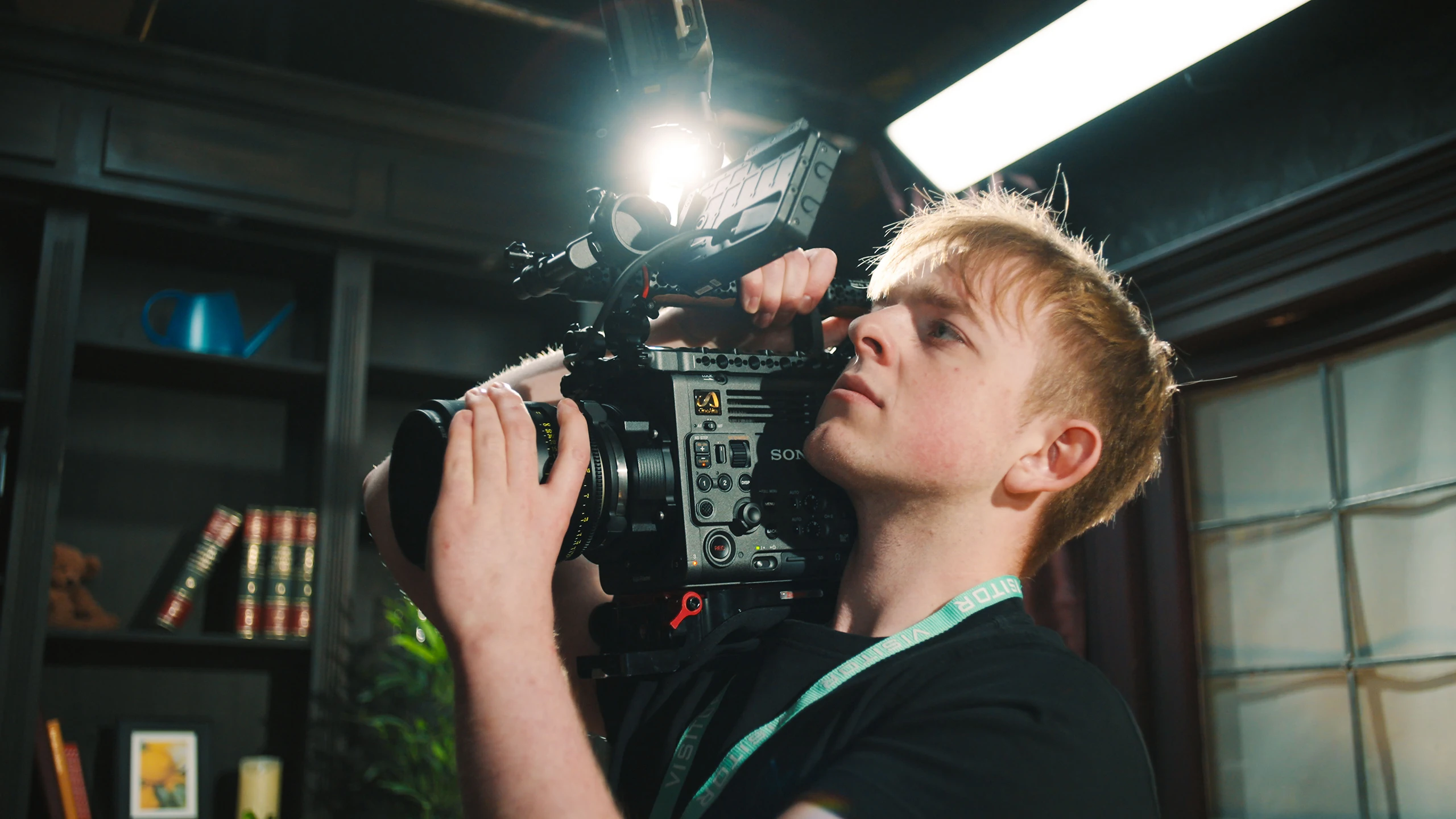 A camera operator shooting handheld on a shoulder-mounted cinema camera